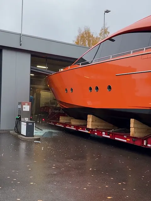 Oranssi superjahti lavetilla on törmännyt huoltoaseman autopesulan oviaukkoon, maassa lasinsirpaleita.